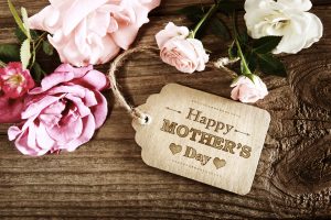 Mothers Day message with small pink roses on wooden table